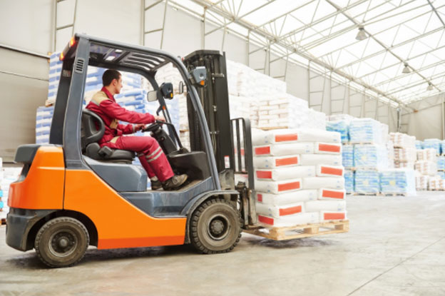 Orange counterbalance forklift moving loaded pallets